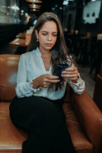 A woman sitting in a chair looking at her phone